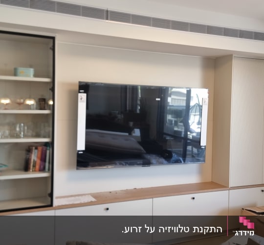 ארון עם מדפים, טלוויזיה מותקנת על הקיר, קופסאות קרטון על הרצפה